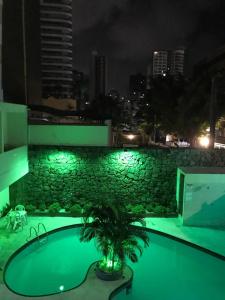 a building with a palm tree on the roof at night at Hotel Italia Beach in Fortaleza