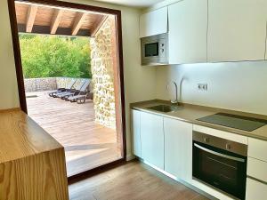 a kitchen with white cabinets and a sliding glass door at 2 Apartamentos en villa con piscina privada en Asturias El Marquesau in Noriega