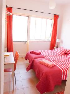 two beds in a room with red curtains at Casa do Lado in Carrapateira