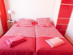 two beds in a small room with red and white stripes at Casa do Lado in Carrapateira