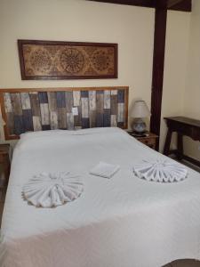 un letto bianco con due asciugamani sopra di Pousada Bonns Ventos a Ilhabela