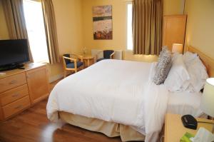 a bedroom with a large white bed and a television at Smugglers Cove Inn in Lunenburg