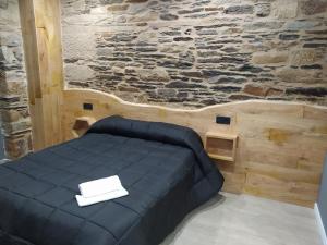 Cama en habitación con pared de piedra en Apartamentos turísticos o palomar, en Vilalba
