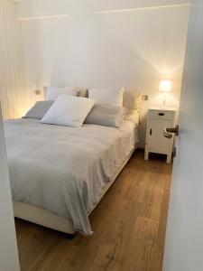 ein Schlafzimmer mit einem weißen Bett mit einem Nachttisch und einem Bett mit einem sidx sidx sidx. in der Unterkunft Appartamento San Pellegrino in Passo San Pellegrino