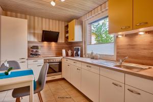 a kitchen with white cabinets and a sink and a window at Ferienhaus Werner in Liebenburg