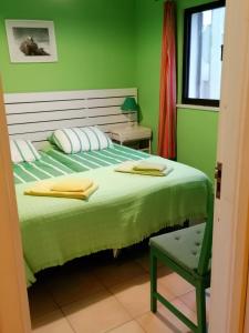 a green bedroom with a bed and a chair at Casa do Lado in Carrapateira