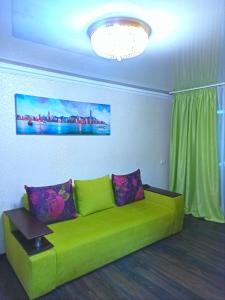 a green couch in a living room with a chandelier at Apartments in the Center of the city in Dnipro