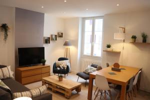 een woonkamer met een televisie en een tafel en stoelen bij Le cosy de L'évéche in Marseille