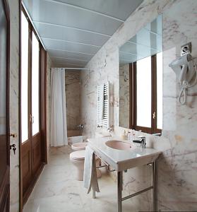 a bathroom with two sinks and a toilet and a mirror at Alba Hotel in Barcelona