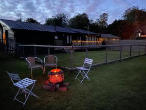 eine Gruppe von Stühlen und eine Feuerstelle in einem Hof in der Unterkunft Spacious Garden Lodge at The Chestnuts, Norfolk in Norwich
