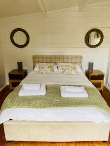 a large bed in a room with two mirrors at Spacious Garden Lodge at The Chestnuts, Norfolk in Norwich