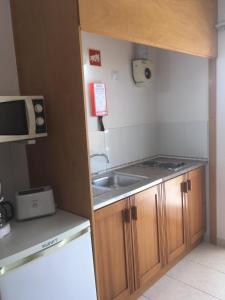 a small kitchen with a sink and a microwave at Vivenda Solmar in Lagos