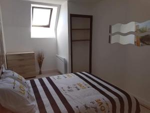 a white bedroom with a bed and a window at La Mouette in Beauvoir