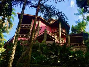 una casa rosa con palmeras delante en Villa Cachoeira da Rocha, en Ilhabela