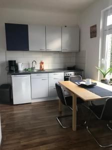 een keuken met witte kasten en een houten tafel bij ALC Zimmervermietung in Brande-Hörnerkirchen