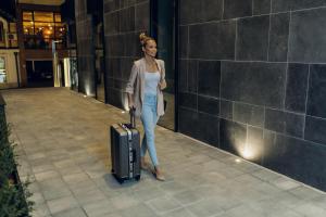 a woman standing with a suitcase on a sidewalk at LUST PREMIUM Apartments in Kragujevac