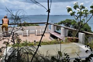 Una mujer parada en un balcón con vistas al océano en Beach Front Village, en Salvador