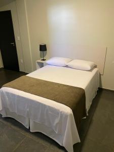 1 dormitorio con 1 cama grande con sábanas y almohadas blancas en Hotel Onda Azul, en Valença