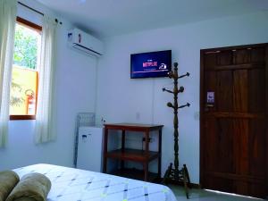 a bedroom with a bed and a tv on the wall at Suítes Estou de Férias Paraty in Paraty