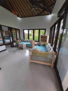 a living room with couches and tables and windows at Villa Gede Private Guest House in Selemadeg