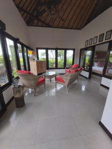 a living room with chairs and a table and windows at Villa Gede Private Guest House in Selemadeg