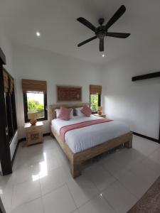 a bedroom with a bed with a ceiling fan at Villa Gede Private Guest House in Selemadeg