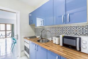 cocina azul con fregadero y microondas en Mirador del Mar Sea Point Apartament, en Maspalomas 21 fotos más