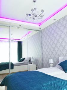 a bedroom with a blue bed and pink lighting at Apartament Poezja, Kasprowicza 20a in Kołobrzeg