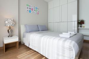 Un dormitorio blanco con una cama con toallas. en Cozy, Great location at heart of Nimman Rd., en Chiang Mai 33 fotos más