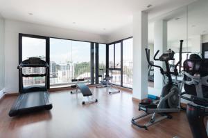 Un gimnasio con cintas de correr y elípticas en una habitación con ventanas. en Cozy, Great location at heart of Nimman Rd., en Chiang Mai