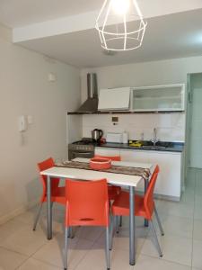 een keuken met een witte tafel en rode stoelen bij Monoambiente Libertad 345 in Puerto Madryn