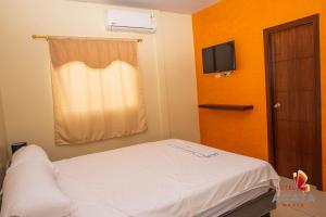 um pequeno quarto com uma cama e uma janela em Hotel Ágata Manta em Manta