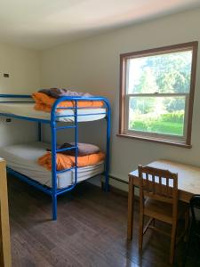 a room with bunk beds and a table and a window at Vancouver Backpacker House in Burnaby