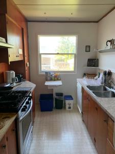een keuken met een fornuis, een wastafel en een raam bij Vancouver Backpacker House in Burnaby