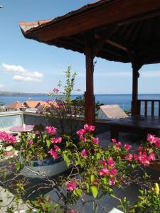 eine Terrasse mit rosa Blumen und einer Pergola in der Unterkunft Sony Home Stay in Amed