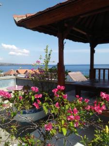 a patio with pink flowers and a pergola at Sony Home Stay in Amed