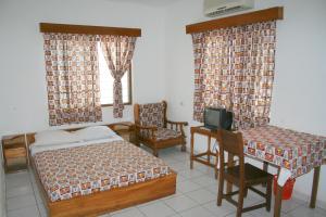 a bedroom with two beds and a desk and a tv at Hotel Aurore Lomé in Lomé