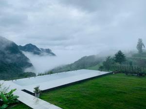 a long white building in a field with a foggy mountain at Purespace in Zhangjiajie