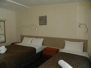 
a hotel room with two beds and two lamps at Coachman Motel in Toowoomba

