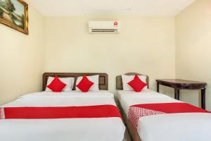 two beds with red pillows in a room at Super OYO 89427 Kavanas Hotel Taiping in Taiping