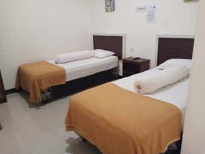 two beds in a hotel room with two bedsskirts at Fidelia Homestay Palu Mitra RedDoorz in Biromaru
