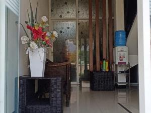 a hallway with chairs and a vase of flowers on a table at Fidelia Homestay Palu Mitra RedDoorz in Biromaru