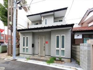 a gray house with a door on a street at COTO Tokyo Koenji in Tokyo