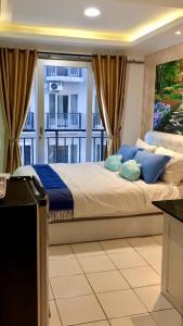 a bedroom with a bed with blue pillows and a window at Apartment Grand Asia Afrika Tulip Bandung in Bandung