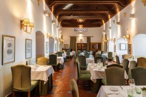 a dining room with white tables and green chairs at Parador de Oropesa in Oropesa