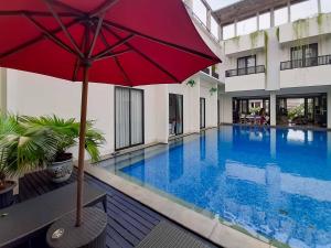 ein großer Pool mit einem roten Regenschirm neben einem Gebäude in der Unterkunft Bangka Suite Mitra RedDoorz in Jakarta