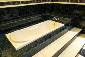 uma banheira numa casa de banho com azulejos pretos em MK Homestay Wakaf Che Yeh with bathtub - Max 14 Pax em Kota Bharu
