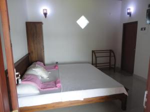 een slaapkamer met een groot bed met roze en witte kussens bij Sapara River Guest in Bentota