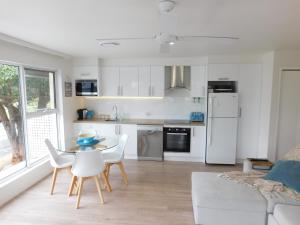 a kitchen with white cabinets and a table and chairs at Secret at Huskisson in Huskisson