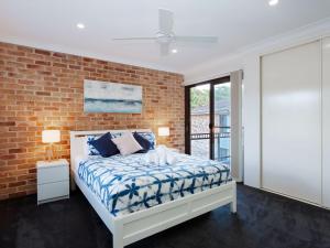 Un dormitorio con una cama y una pared de ladrillo. en Bay Parklands, 68 2 Gowrie Ave - Fully ducted aircon, wifi, pool, tennis court, communal spa, en Shoal Bay